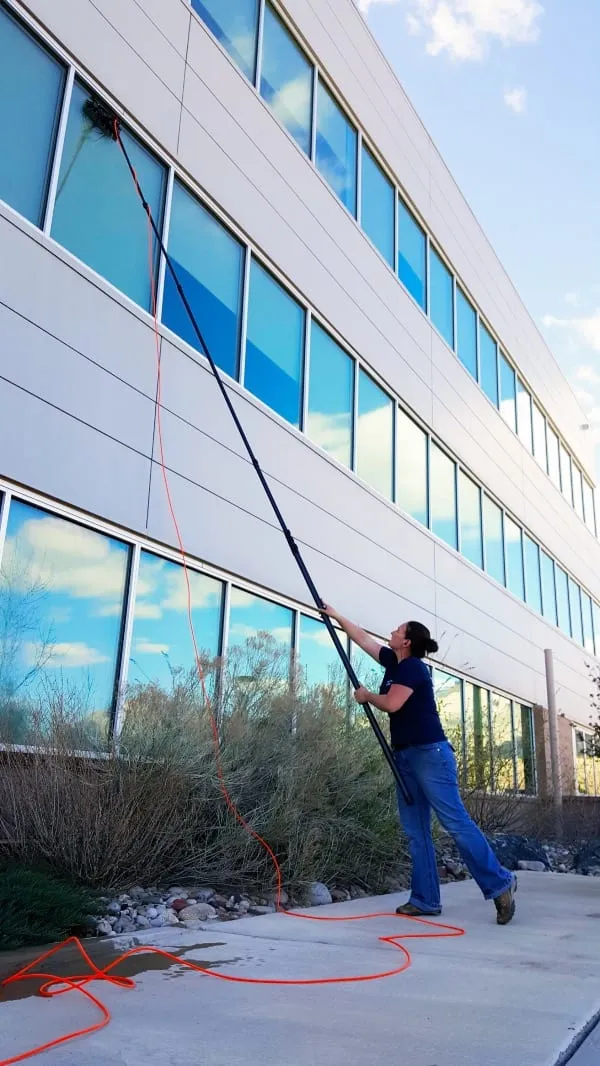 Technician cleaning a three-story commercial building with a pure-water pole