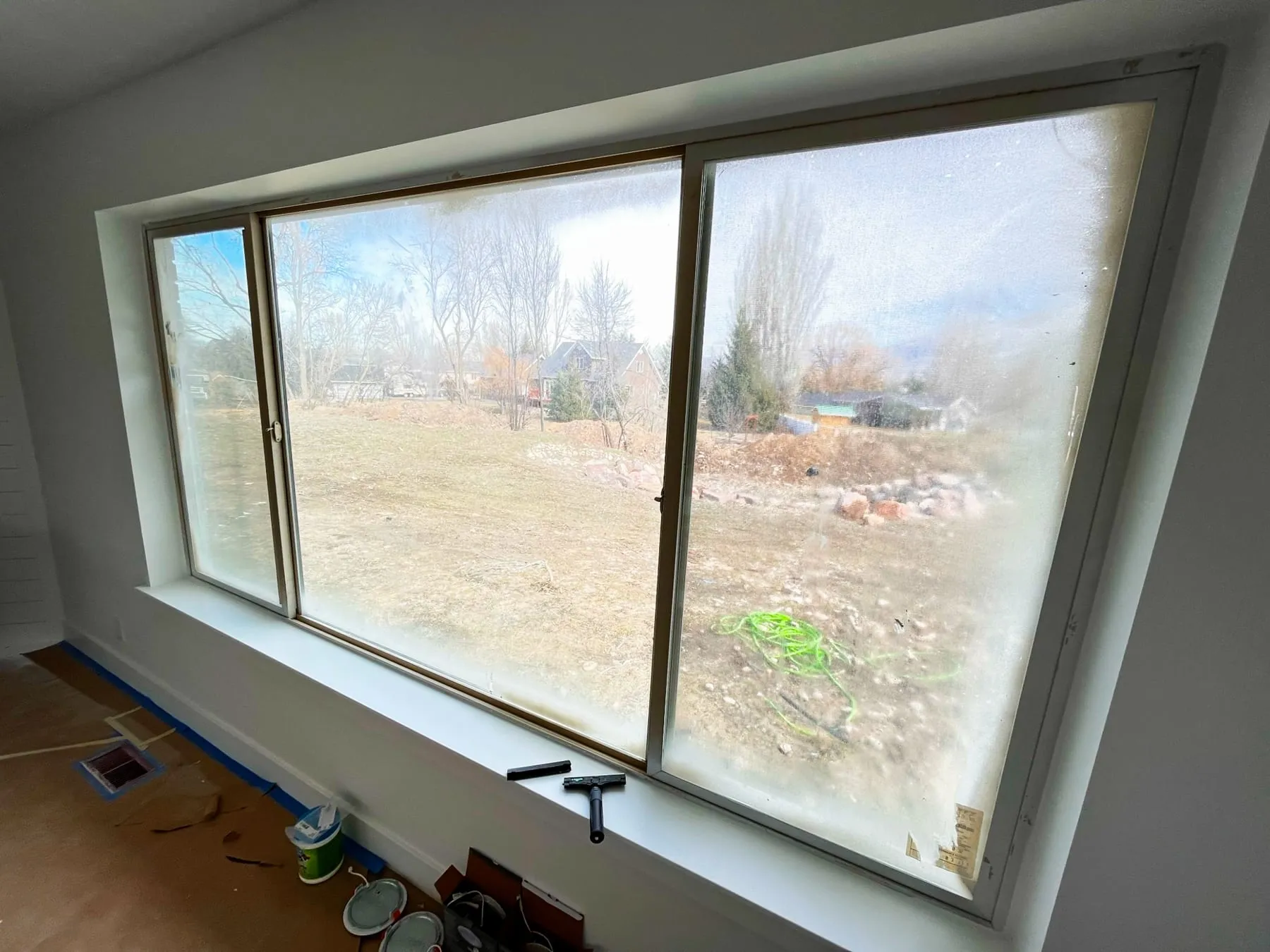 Foggy, mineral-stained picture window before cleaning